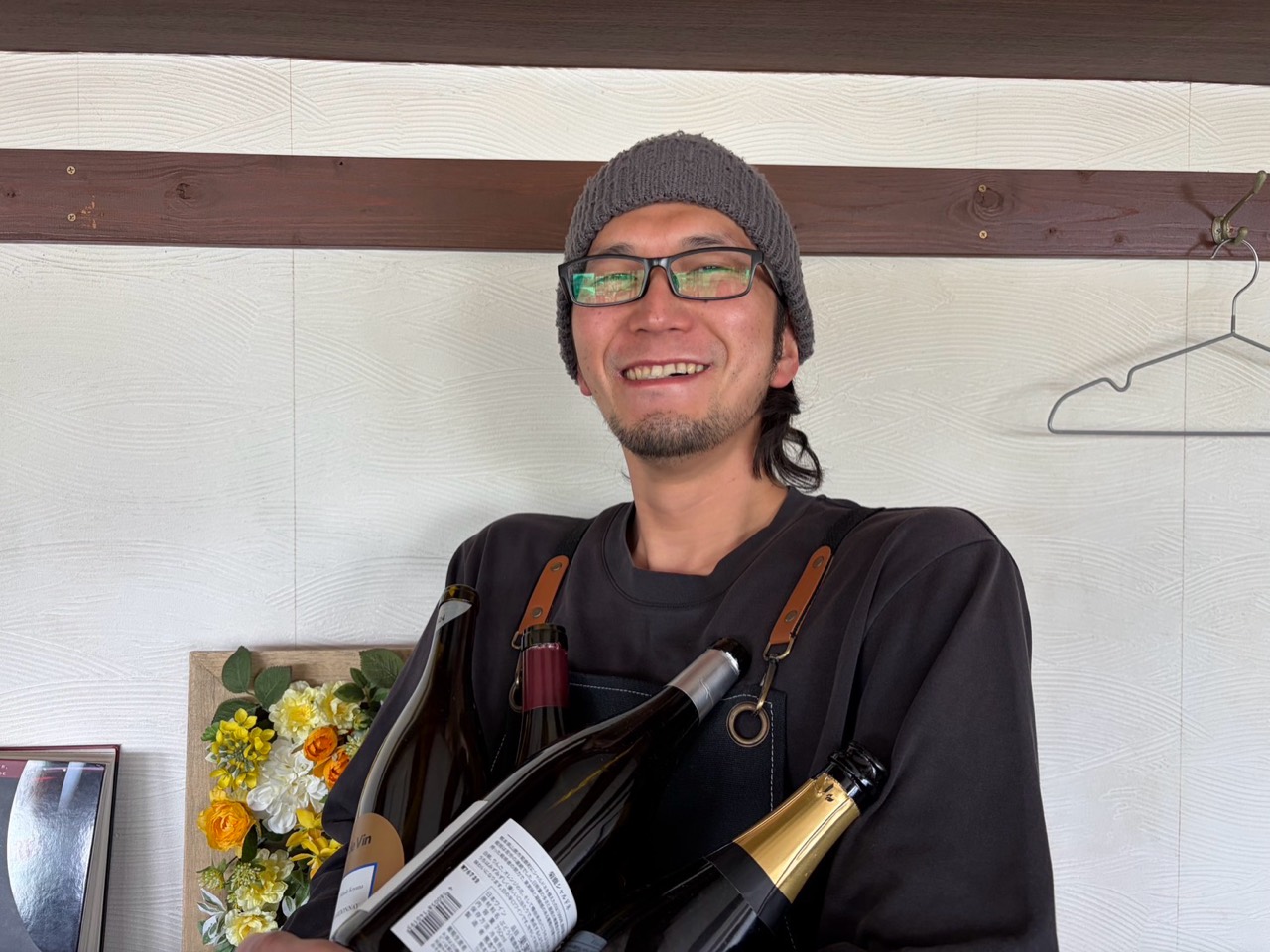 ワインボトルを抱えて笑顔で迎える店主・古賀真人